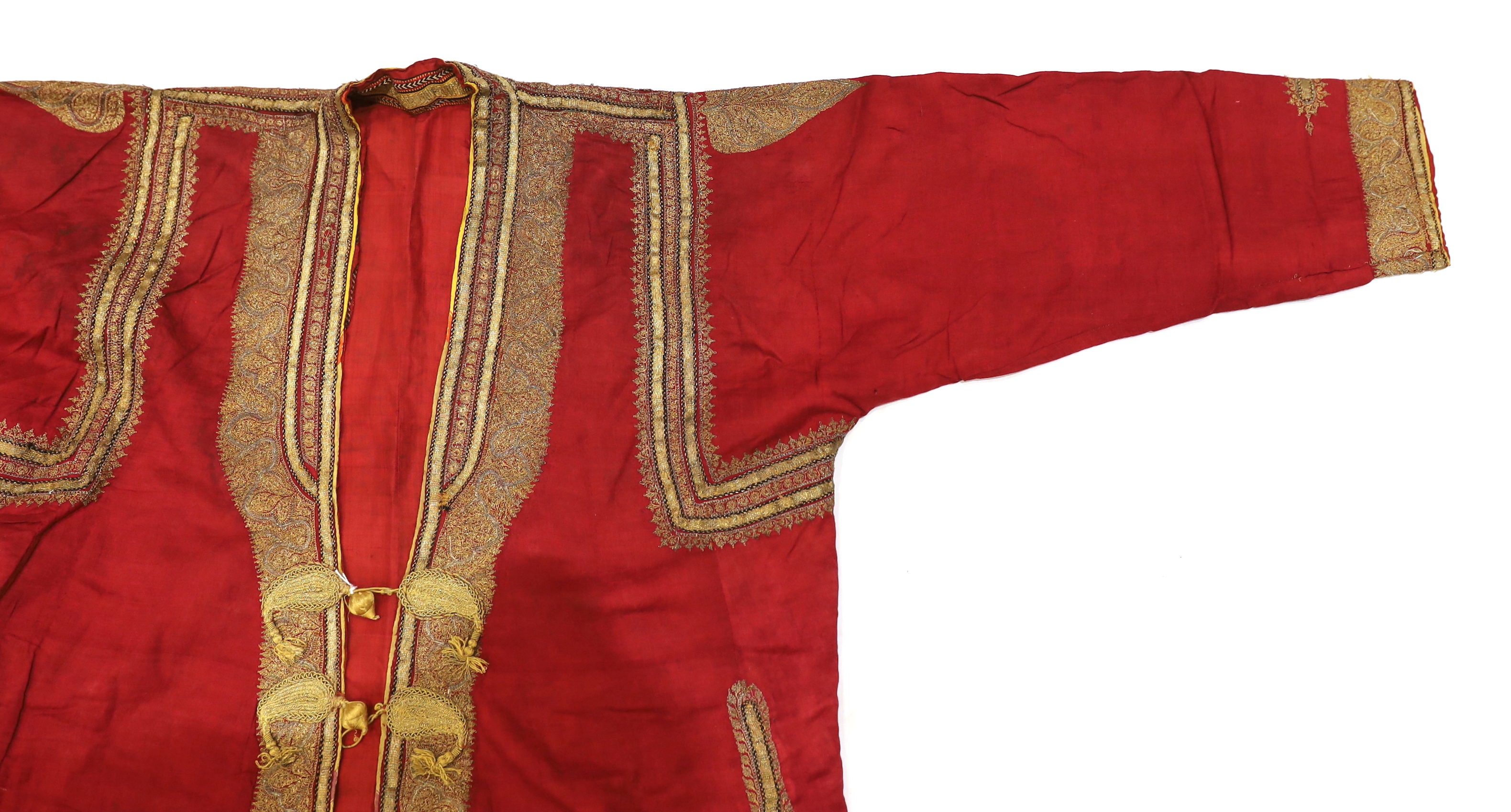 A late 19th century gentleman’s quilted red silk Indian Chogha, embroidered with ornate gold and silver metallic thread borders and paisley design details